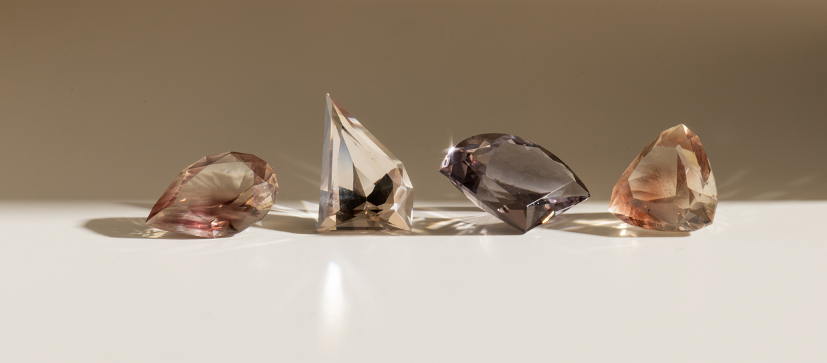 Four different colored diamonds on a reflective surface with a neutral background