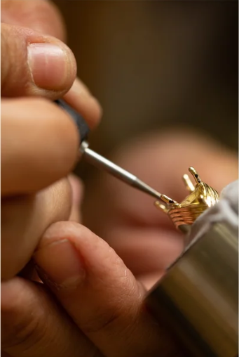 Bench jeweler hand-setting a stone on a gold ring during the BLACKLABEL fabrication process